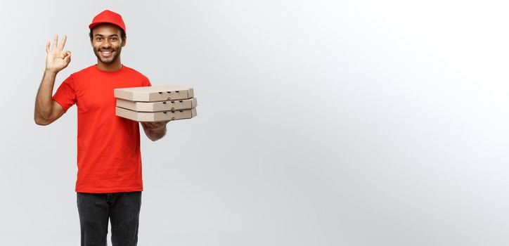 Delivery Concept - Portrait of Handsome African American Pizza delivery man making ok sign with fingers. Isolated on Grey studio Background. Copy Space