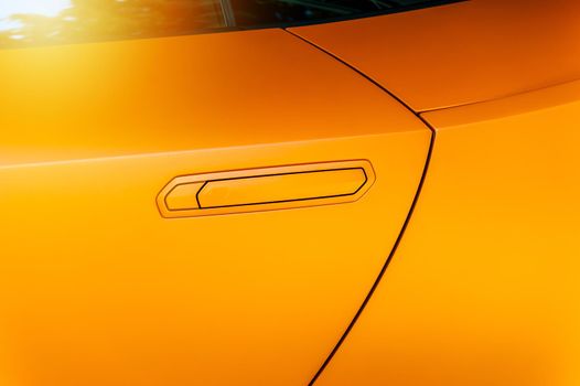 Car door handle of an orange modern car: background