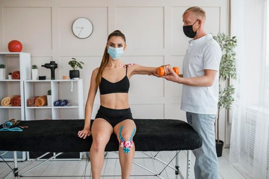 female patient physiotherapy with man dumbbell