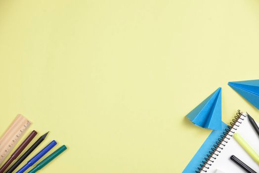 folded blue papers with office stationeries against yellow backdrop with space writing text