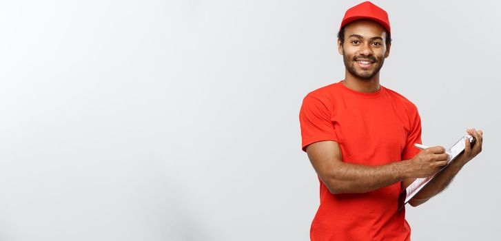 Delivery Concept - Portrait of Handsome African American delivery man or courier writing on a order document. Isolated on Grey studio Background. Copy Space