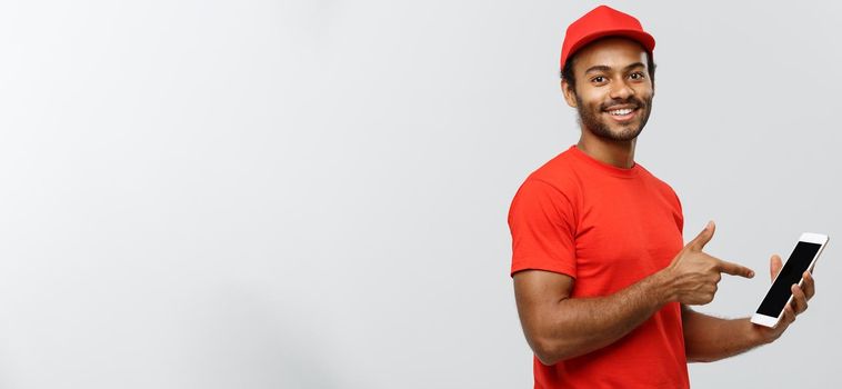 Delivery Concept - Portrait of Handsome African American delivery man or courier showing tablet on you to check the order. Isolated on Grey studio Background. Copy Space