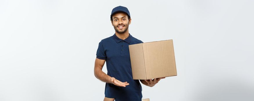 Delivery Concept - Portrait of Happy African American delivery man pointing hand to present a box package. Isolated on Grey studio Background. Copy Space