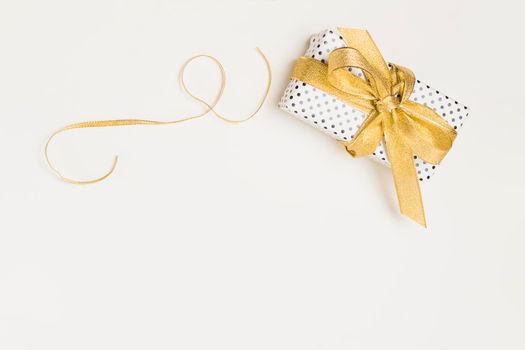 elevated view present box wrapped polka dot design paper with shiny golden ribbon isolated white backdrop