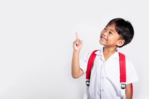 Asian toddler smiling happy wear student thai uniform red pants keeps pointing finger at copy space in studio shot isolated on white background, Portrait little children boy preschool, Back to school