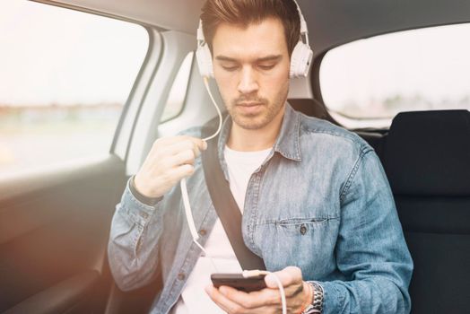 young man listening music headphone while travelling car