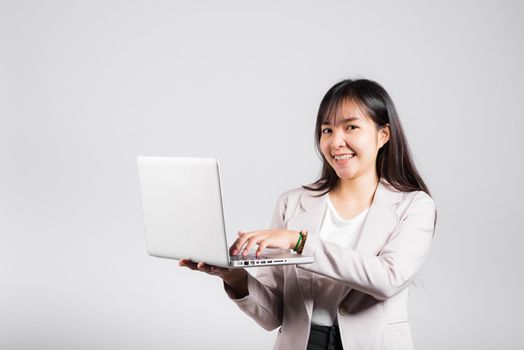 Woman smiling confident smiling holding using laptop computer and typing keyboard for online sending email or chat, Portrait excited happy Asian young female studio shot isolated on white background