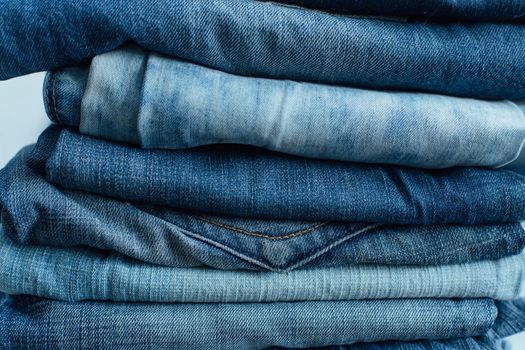 Stack of a stack of old jeans various shades of blue jeans. Denim jeans texture. Denim background texture for design. Canvas denim texture. Blue denim background.