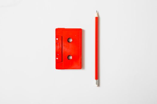 red cassette tape pencil white background