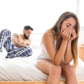 upset woman sitting bed front her husband
