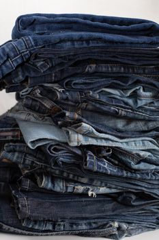 Stack of a stack of old jeans various shades of blue jeans. Denim jeans texture. Denim background texture for design. Canvas denim texture. Blue denim background.