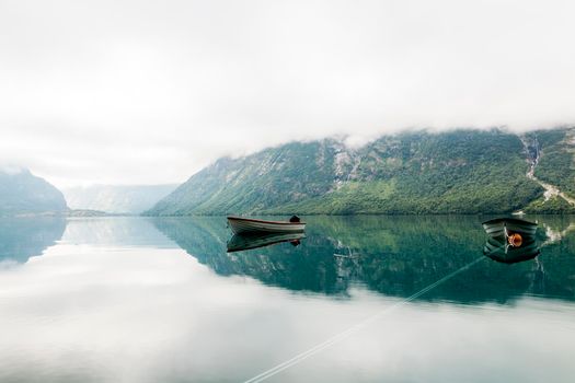 lonely boats calm lake with misty mountain background