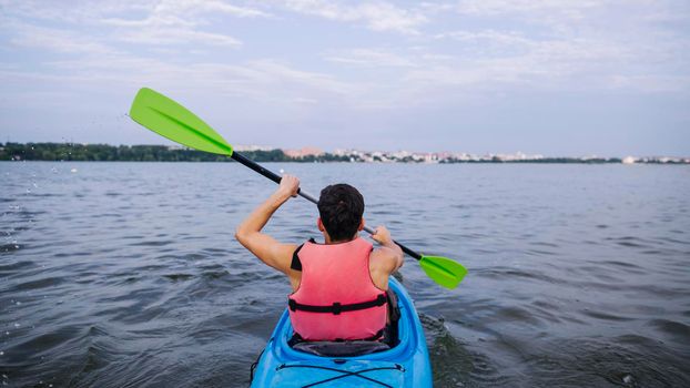 rear view male kayaker paddling kayak