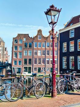 amsterdam city center with typical buildings and bicycles parked on the bridge crossed by the river, travel reportage