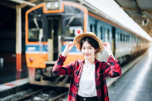 summer, relax, vacation, travel, portrait of cute Asian girl showing smile and showing joy while waiting at the train station for a summer trip