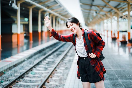 summer, relax, vacation, travel, portrait of a cute Asian girl showing smiles and waving to friends who are arriving at the train station waiting for their trip