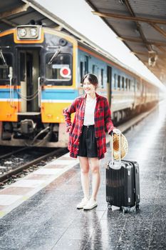 summer, relax, vacation, travel, portrait of cute Asian girl showing smile and showing joy while waiting at the train station for a summer trip