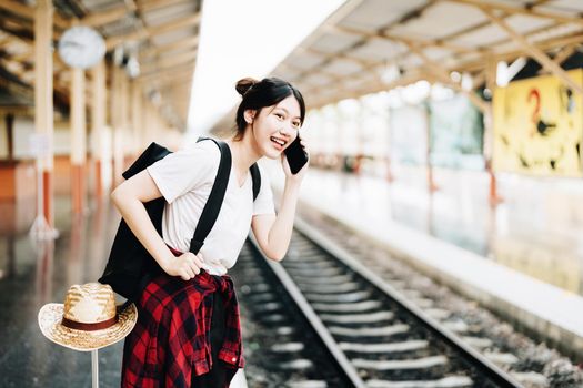 summer, relax, vacation, travel, portrait of beautiful Asian girl using the smartphone mobile to call friends at the train station while waiting for their travel time