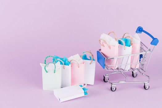 many colorful paper shopping bags cart pink background