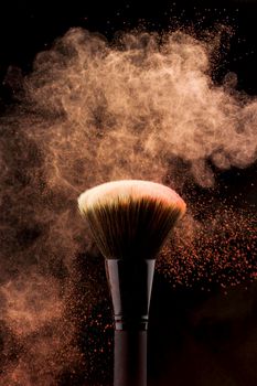 makeup brush with peach color powder splash