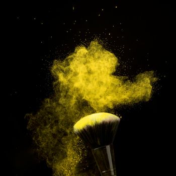 makeup brush yellow powder dust dark background