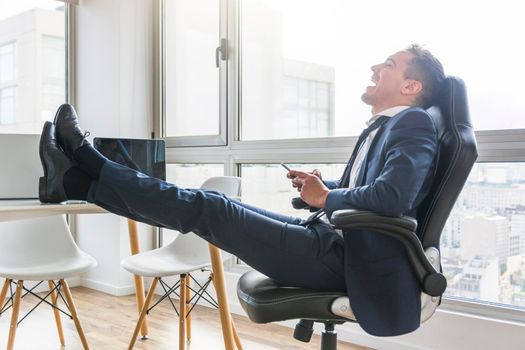 happy businessman sitting chair workplace using mobile