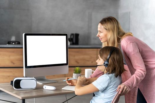 girl with headset learning online with mother by her side