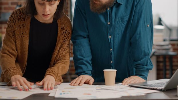 Man and woman brainstorming ideas and looking at rate charts to design business project. Colleagues working together on presentation planning, analyzing papers. Team of workmates