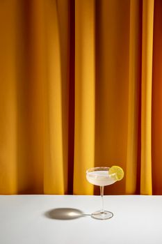 lime cocktail saucer glass white table against yellow curtain