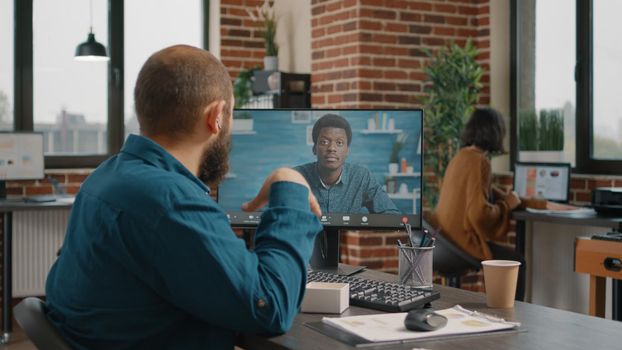 Entrepreneur using video call communication to talk to colleague about business project and planning. Man meeting manager on online video conference, using computer monitor on desk