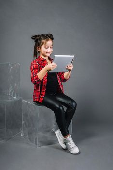 little girl sitting block looking digital tablet against gray background