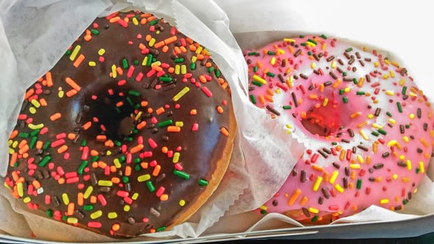 two sweet colored donuts with delicious glace, wrapped and ready to serve 