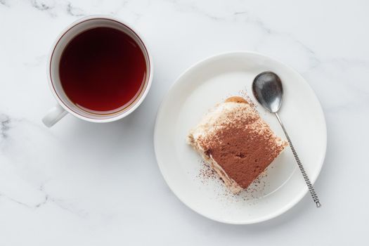 Piece of Homemade Tiramisu cake dessert and coffee on a white marble background