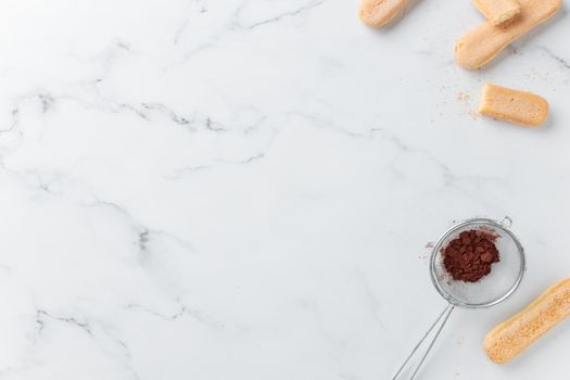 Tiramisu ingredients: Italian cookie savoiardi and cocoa powder top view on a white background