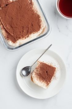 Piece of Homemade Tiramisu cake dessert and coffee on a white marble background