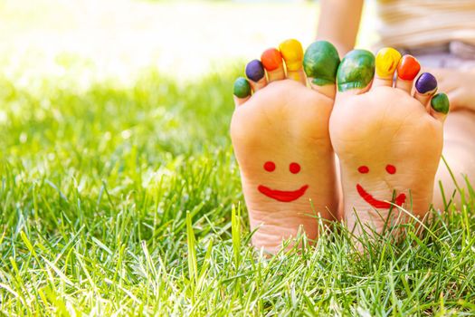 Children's feet with a pattern of paints smile on the green grass. Selective focus. nature.
