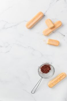 Tiramisu ingredients: Italian cookie savoiardi and cocoa powder top view on a white background