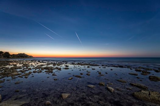 an amazing tranquil scene of a rocky shore before sunrise. Blue hour