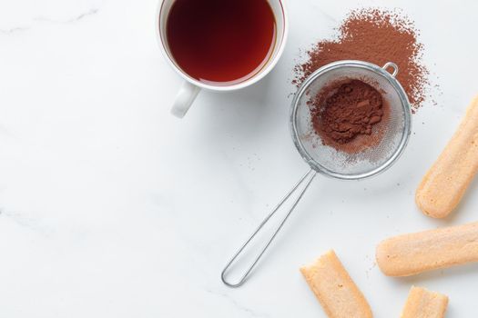 Tiramisu ingredients: Italian cookie savoiardi, coffee and cocoa powder top view on a white background