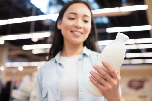 cheerful asian female holding bottle milk supermarket