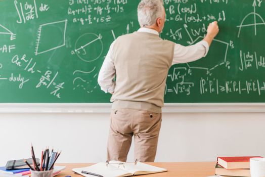 aged math teacher writing equation chalkboard