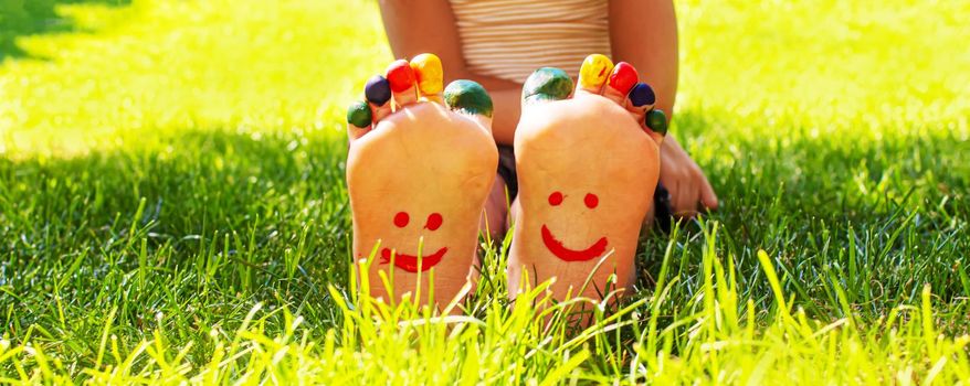 Children's feet with a pattern of paints smile on the green grass. Selective focus. nature.