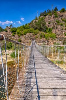 Wooden rope suspension bridge for walk crossing river in the mountain