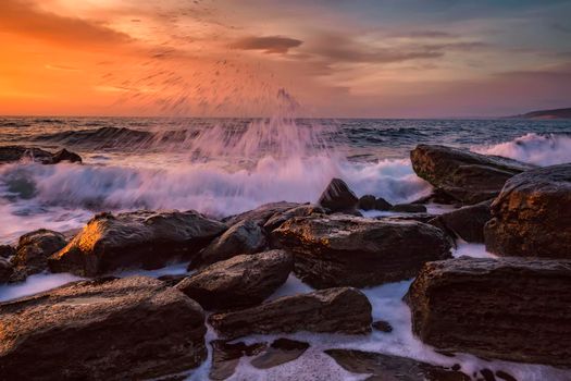 Amazing splash of seawater at morning on the shore of the Black Sea. Beautiful motion blur sea waves over the rocks. 