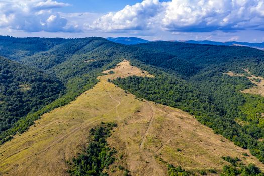 Panoramic Drone Aerial View view of mountain peaks. Hilltops covered with forest. Green nature background aerial view mountain landscape.