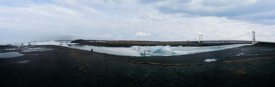 Jokulsarlon lagoon icebergs canal to the ocean wide panorama with suspension bridge