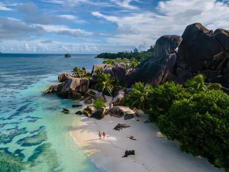 Anse Source d'Argent beach, La Digue Island, Seyshelles, Drone aerial view of La Digue Seychelles bird eye view.of tropical Island, couple men and woman walking at the beach during sunset at a luxury vacation