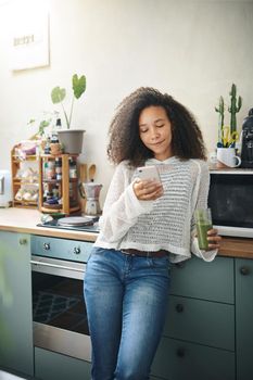 Girl browsing on social media while enjoying her green smoothie. High resolution stock photo