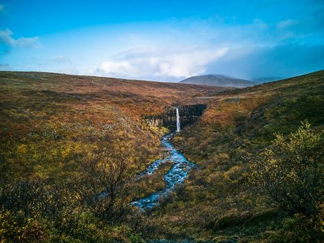 Svartifoss waterfall top wide angle view in Skaftafell National Park with tourists on autumn