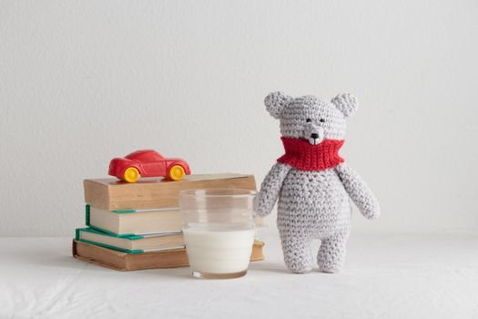 Crochet knitting cute teddy bear with books and a toy on a white table